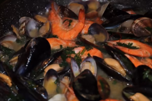Moules palourdes et crevettes ouvertes fremissant dans le bouillon parfume au persil