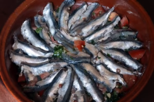 Anchois ouverts disposés en rosace dans un plat rond en terre cuite