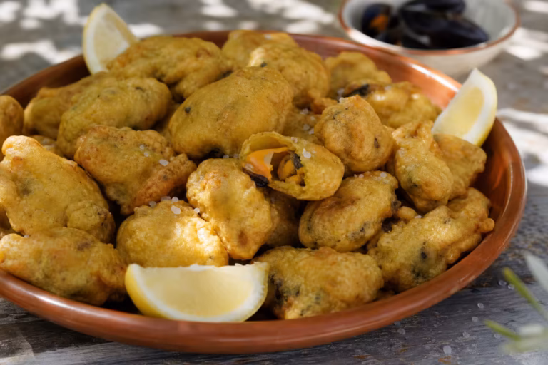 Beignets de moules de Sète dorés servis dans un plat de partage rustique