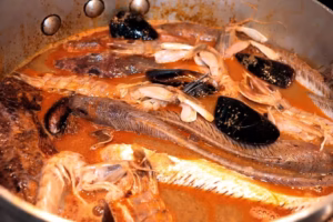Poissons et moules déposés dans le bouillon chaud de la bouillabaisse sétoise