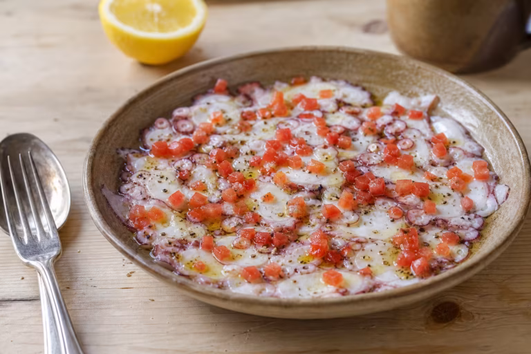 Carpaccio de poulpe en fines tranches avec huile d'olive et tomate