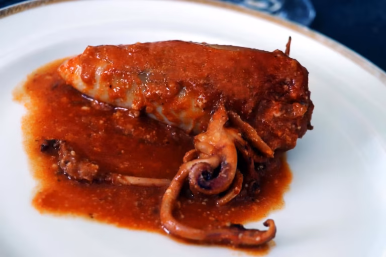 Encornets farcis à la sétoise nappés de sauce tomate dans une assiette
