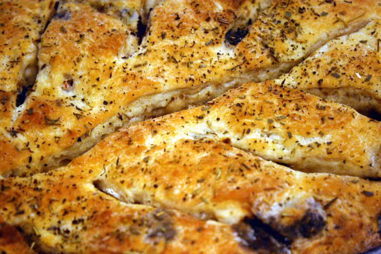 Fougasse aux olives et anchois dorée à la sortie du four, encoches et herbes