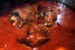 Sauce de macaronade sétoise d'un rouge profond en fin de cuisson avec les brageoles