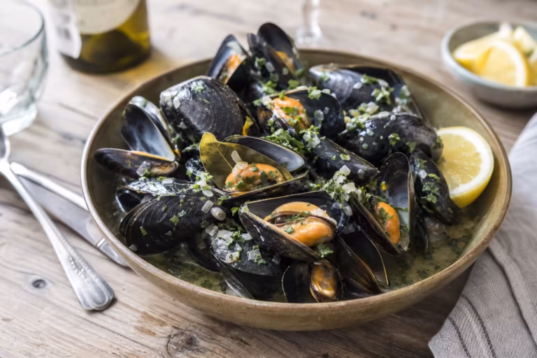 Moules à la marinière au vin blanc et persil dans un bol en terre cuite