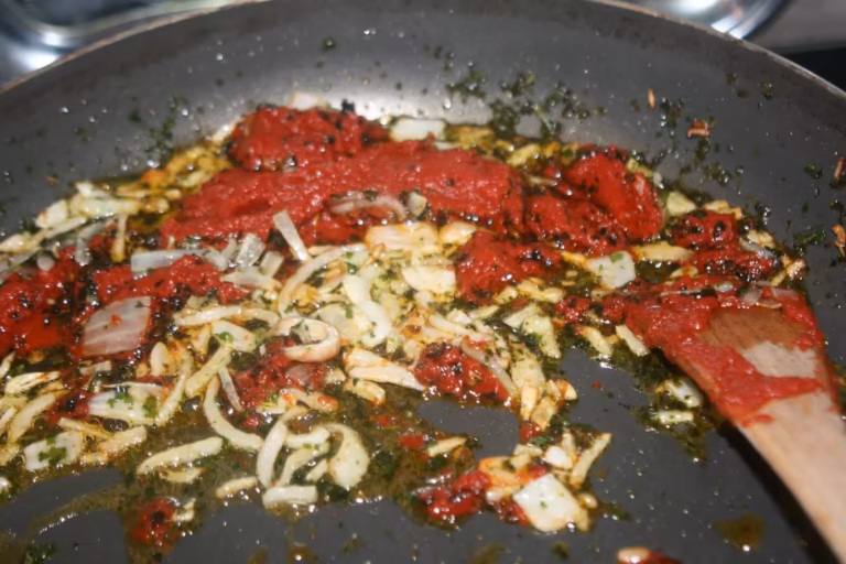 Concentré de tomates ajouté aux oignons et au persil dans la poêle