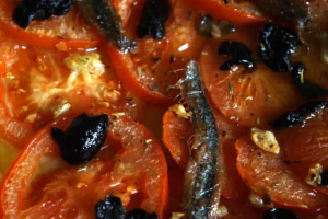 Filet d'anchois, ail et olives noires sur tomates fraîches