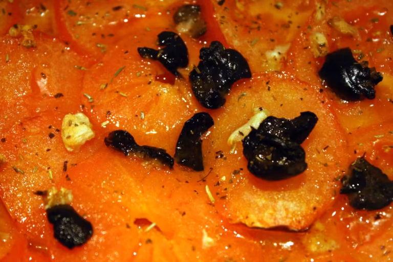 Tranches de tomates et olives noires sur la pizza sétoise
