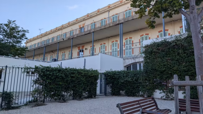 Façade à coursives et volets vert d'eau au-dessus de la placette Damien Macone
