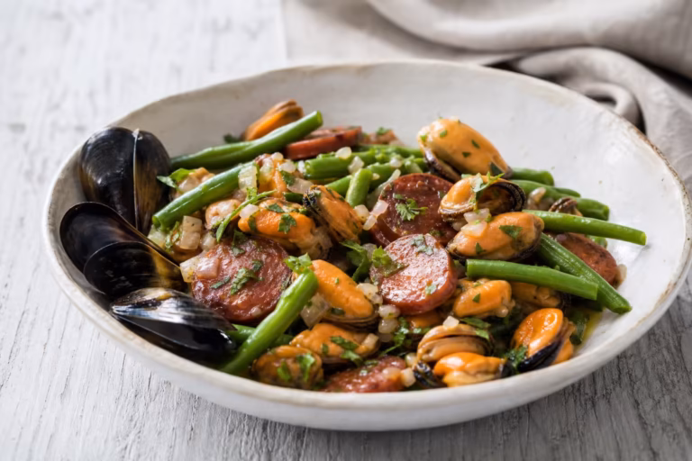 Salade tiède de moules au chorizo et haricots verts dans un bol blanc