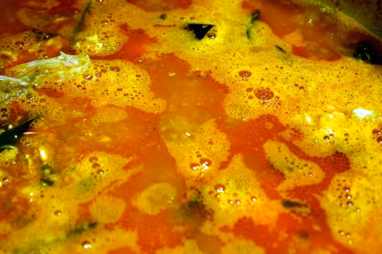 Gros plan sur la mousse orangée de la soupe de poissons en ébullition