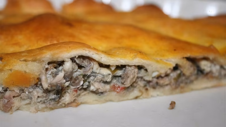 Tielle aux anchois cuite, tranchée, montrant la garniture dorée
