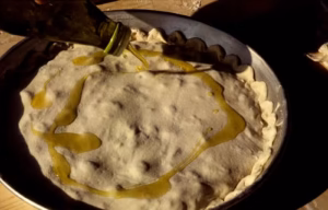 Huile d'olive versée sur la tielle à la scarole avant cuisson