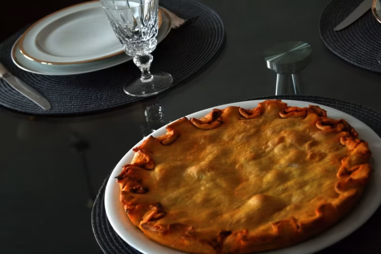 Tielle sétoise cuite servie sur un plat blanc, sur une table dressée