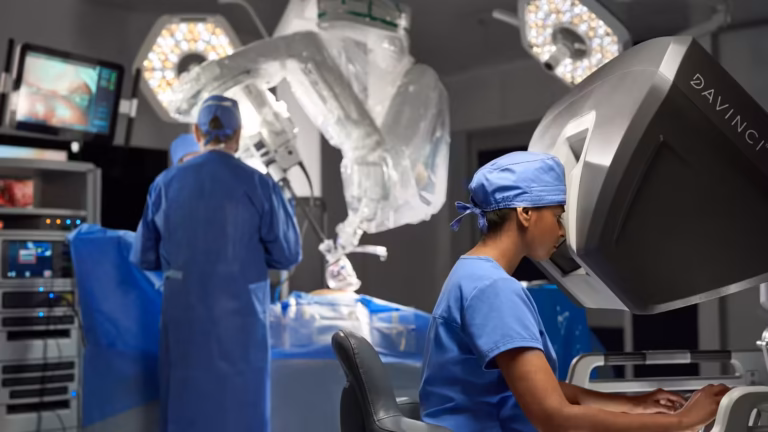 Console da Vinci en salle d'opération : une soignante aux commandes, un collègue près du bras robotisé