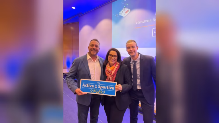 Trois personnes tiennent le panneau Ville Active et Sportive aux trois lauriers 2026 lors de la cérémonie à Paris