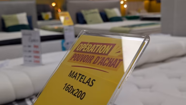Présentoir jaune « Opération pouvoir d'achat » posé sur un matelas 160x200