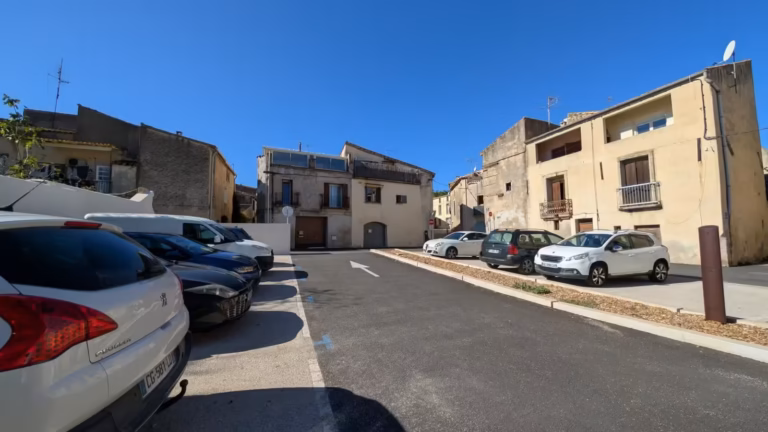 Places de stationnement du parking Sergent Bonnet, maisons du village en fond