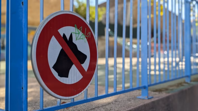 Panneau d'interdiction aux chiens sur la clôture de l'aire de jeux