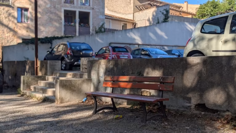 Banc sur l'esplanade, voitures stationnées en arrière-plan