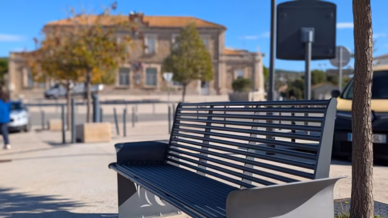 Banc en métal sur l'esplanade face aux bâtiments anciens