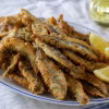 Anchois frits dorés servis sur un plat en faience ancienne avec citron