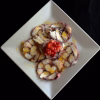 Carpaccio de poulpe en rosaces sur une assiette carrée, brunoise de tomates au centre