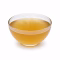 Bol de bouillon de légumes doré translucide sur fond blanc