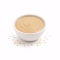 Bol de tahini beige et graines de sésame sur fond blanc
