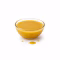 Bol en verre rempli de vinaigrette émulsionnée jaune ambrée sur fond blanc