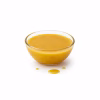 Bol en verre rempli de vinaigrette émulsionnée jaune ambrée sur fond blanc