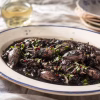 Supions à l'encre en sauce noire persillée sur plat de faïence ancienne