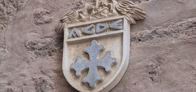Blason à croix occitane sculpté sur une façade d'Agde