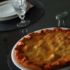 Tielle sétoise cuite servie sur un plat blanc, sur une table dressée